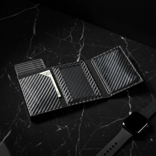 Carbon fiber patterned wallet with card slots and cash compartment on a dark surface.
